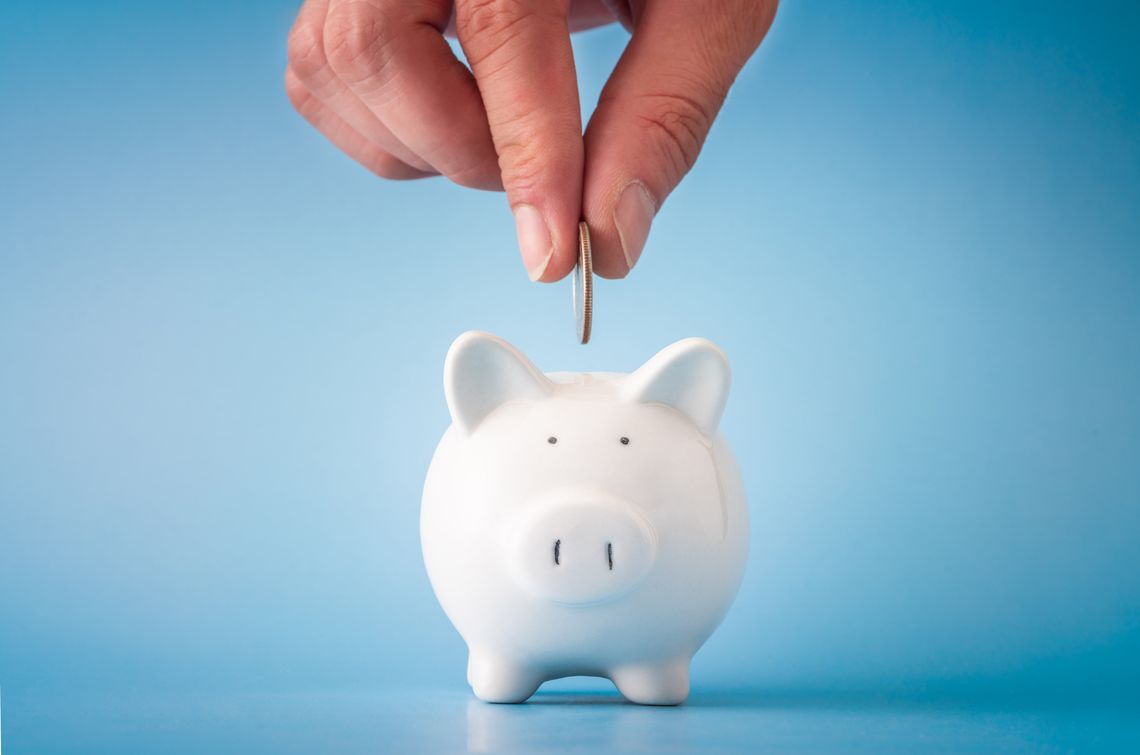 A person depositing a coin into a piggy bank