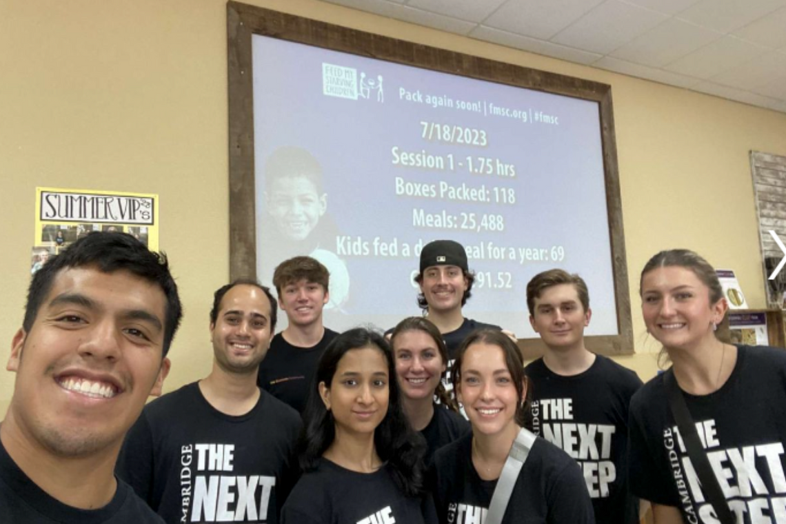 Group of individuals in black shirts smiling for a photo