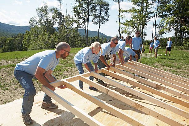 Construction workers lifting up wooden frame of house