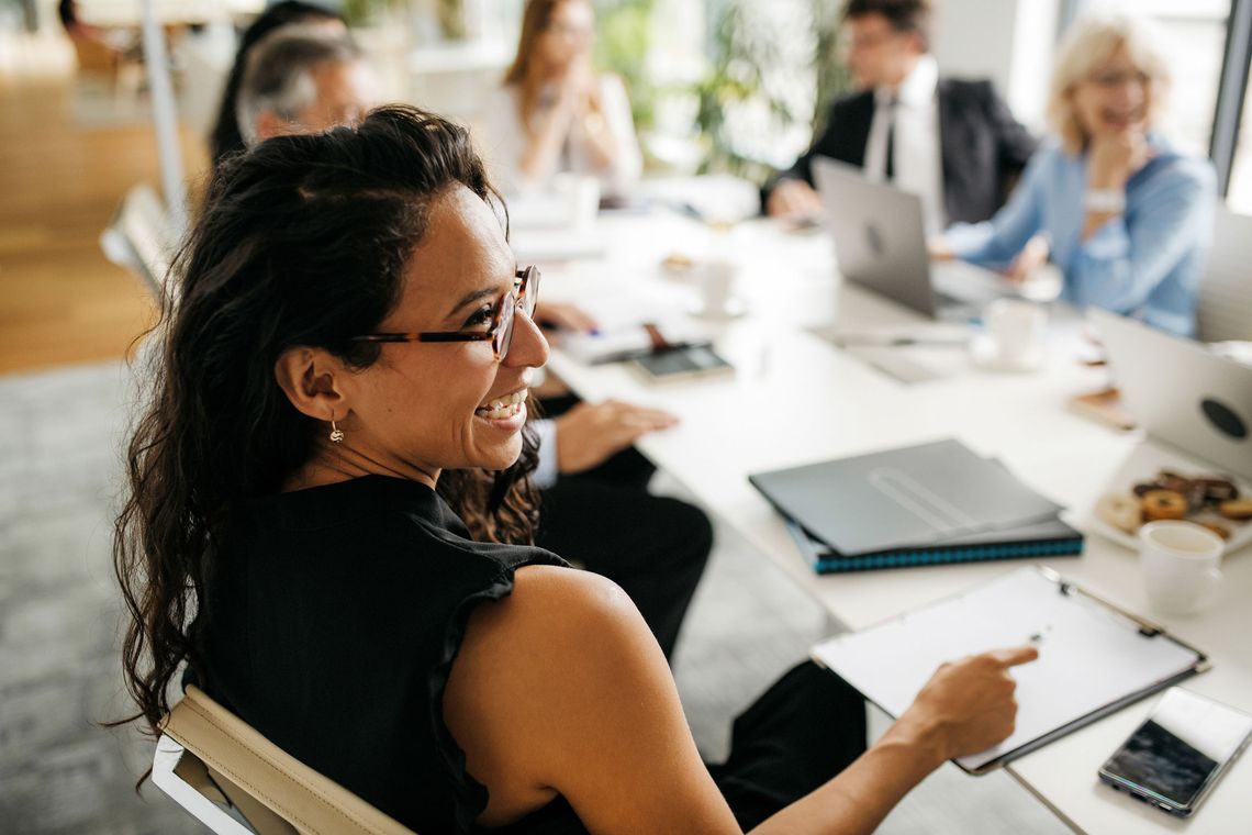 Woman smiling at someone to her right off camera in a meeting