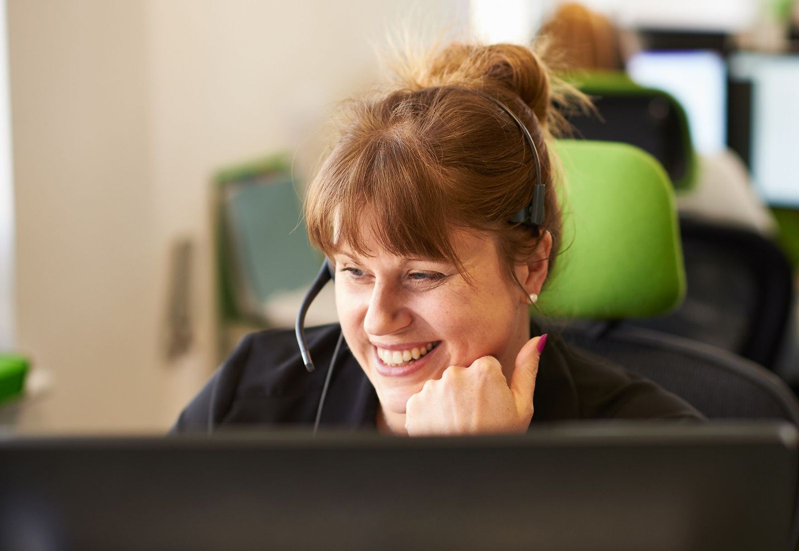 A woman with a headset sits at a desk, focused on her work