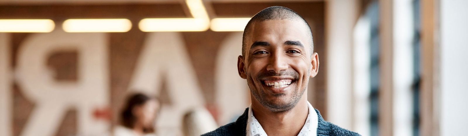 A man smiles warmly in a hallway